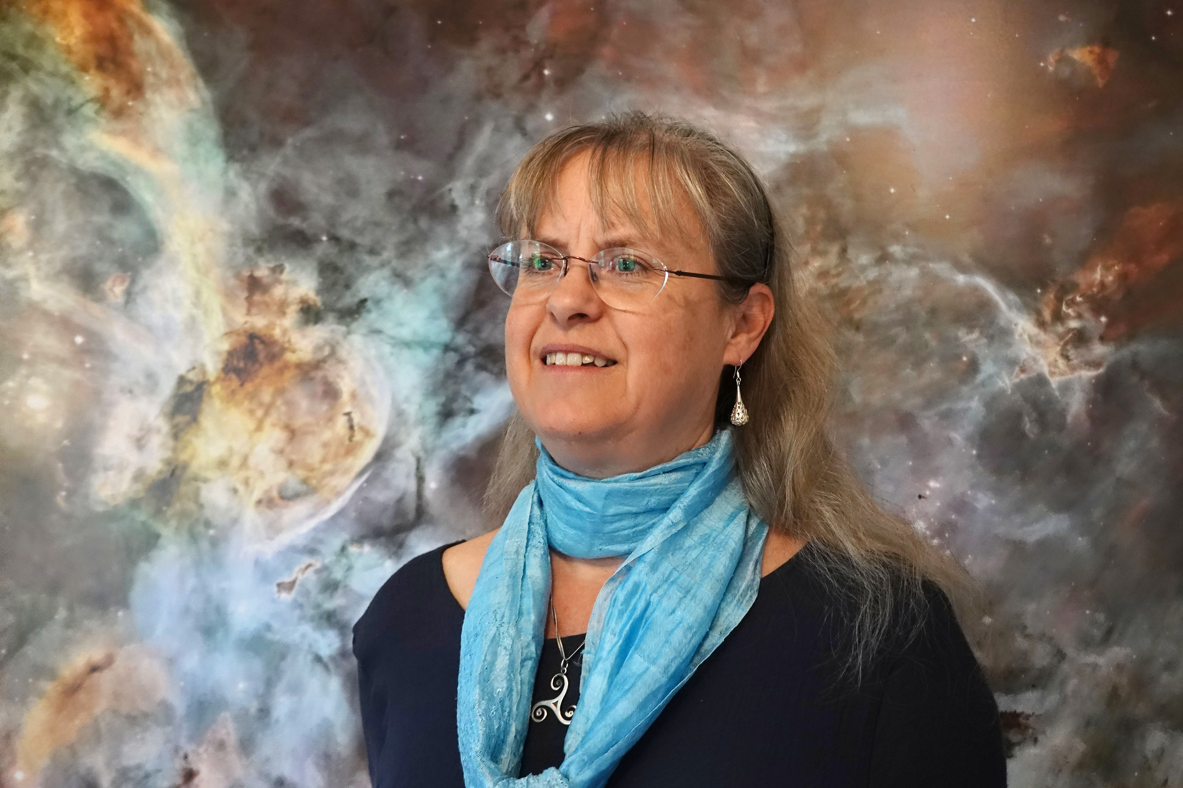 Sylvia Ekström in front of a picture of nebula and stars