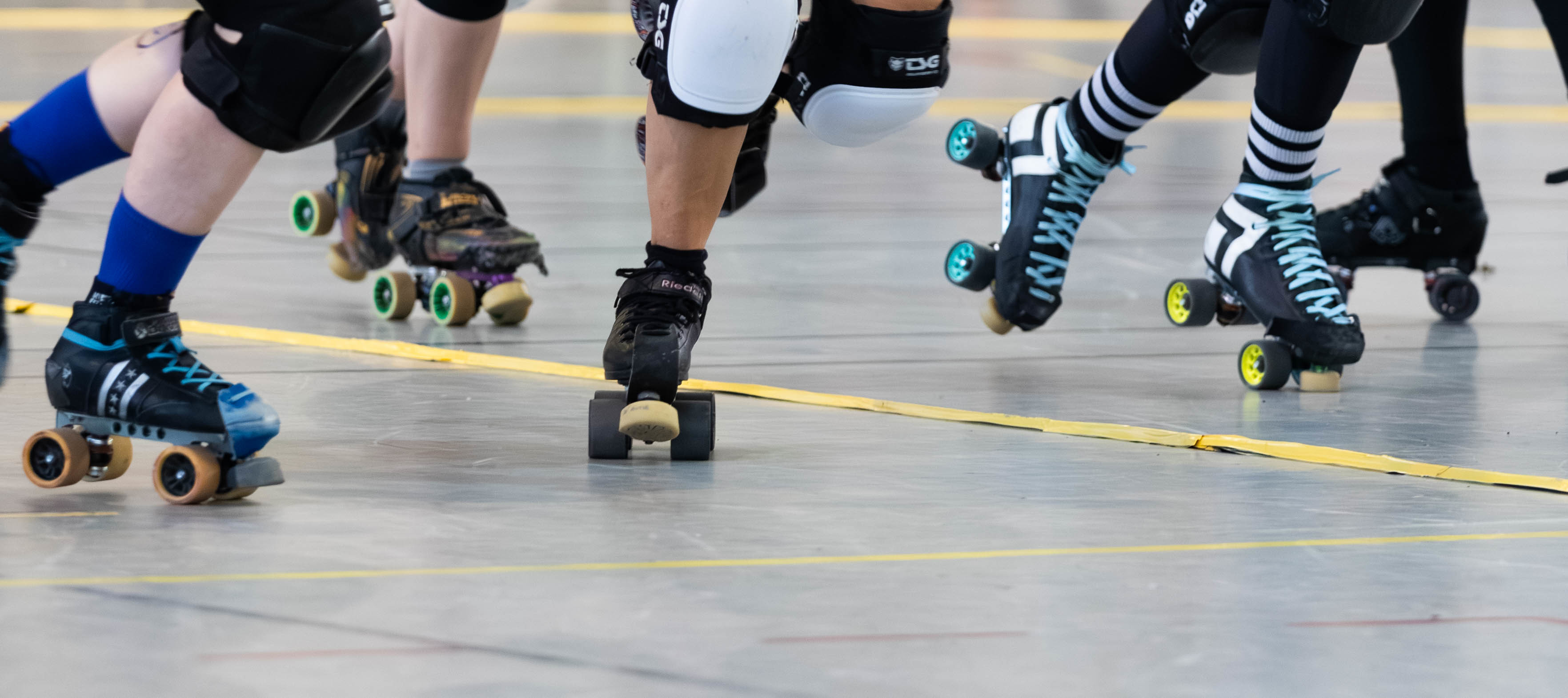 Photo d'un match de derby. On voit que les patins des joueureuses et des arbitres.