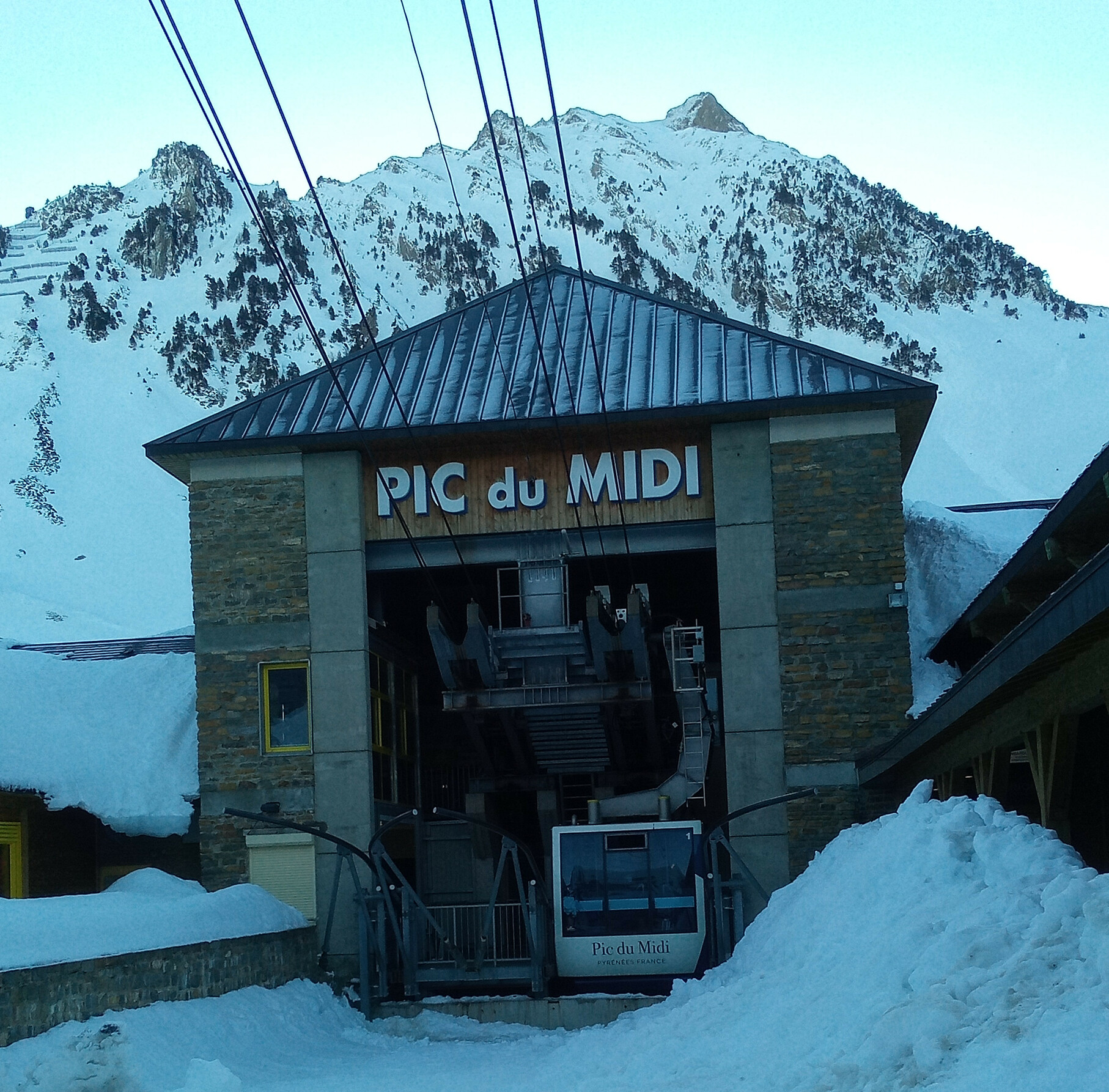 Un télécabine devant une montagne. Il est écrit « Pic du Midi » dessus.